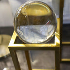 Clear glass sphere on a gold stand with a blurred background