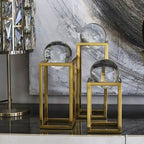 Decorative glass spheres on gold stands against a marble wall.