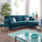 Modern living room with teal sectional sofa and armchair, glass coffee table, and decorative items.