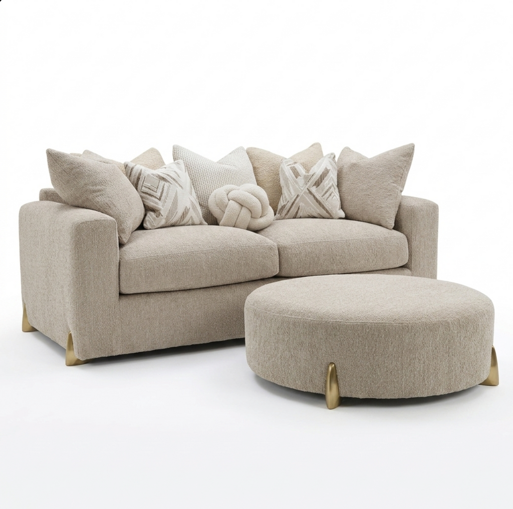 A light beige upholstered sofa with matching accent pillows and a round matching ottoman, shown on a clean white studio background.