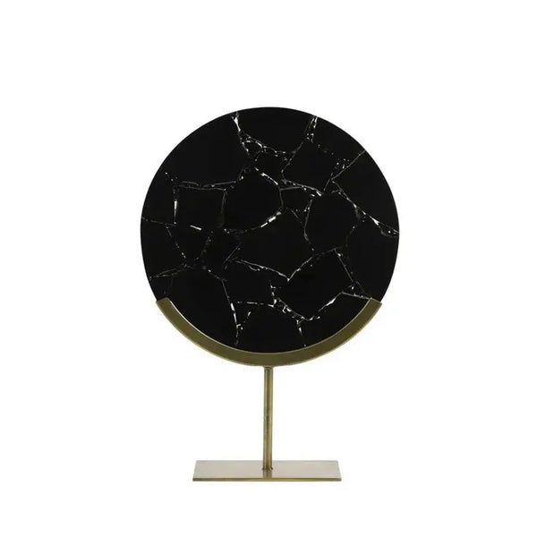 Round black marble table with gold stand on a white background