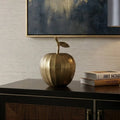 Modern living room with a decorative apple, lamp, and books on a console table.