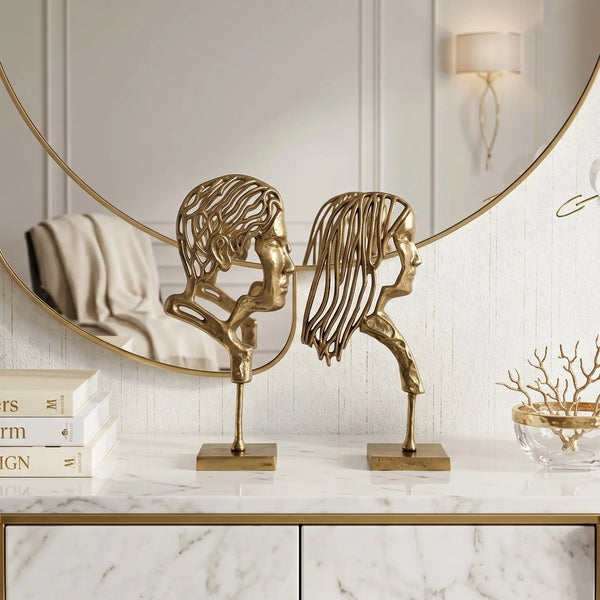 Decorative setup with sculptures, books, and a vase on a marble surface.