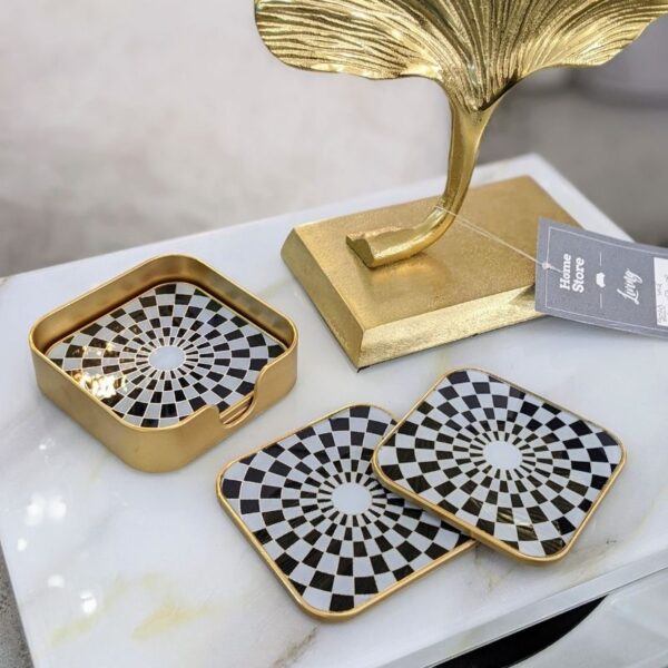 Set of 4 black, white and gold square coasters on white marble table